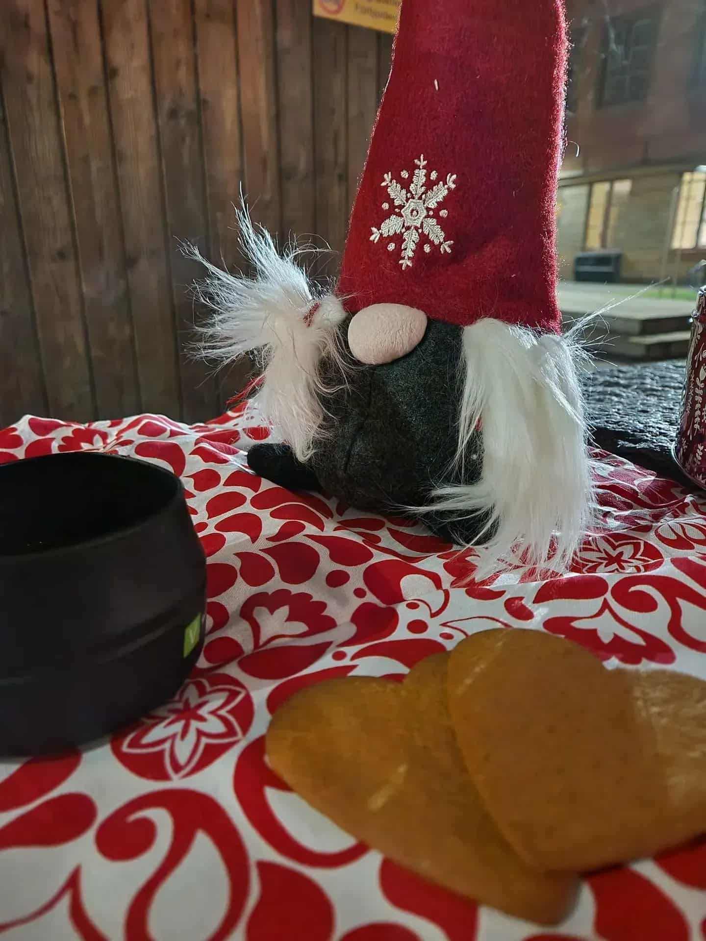 Juldekoration: tomte med röd mössa, vita skägg, pepparkakor och svart mugg