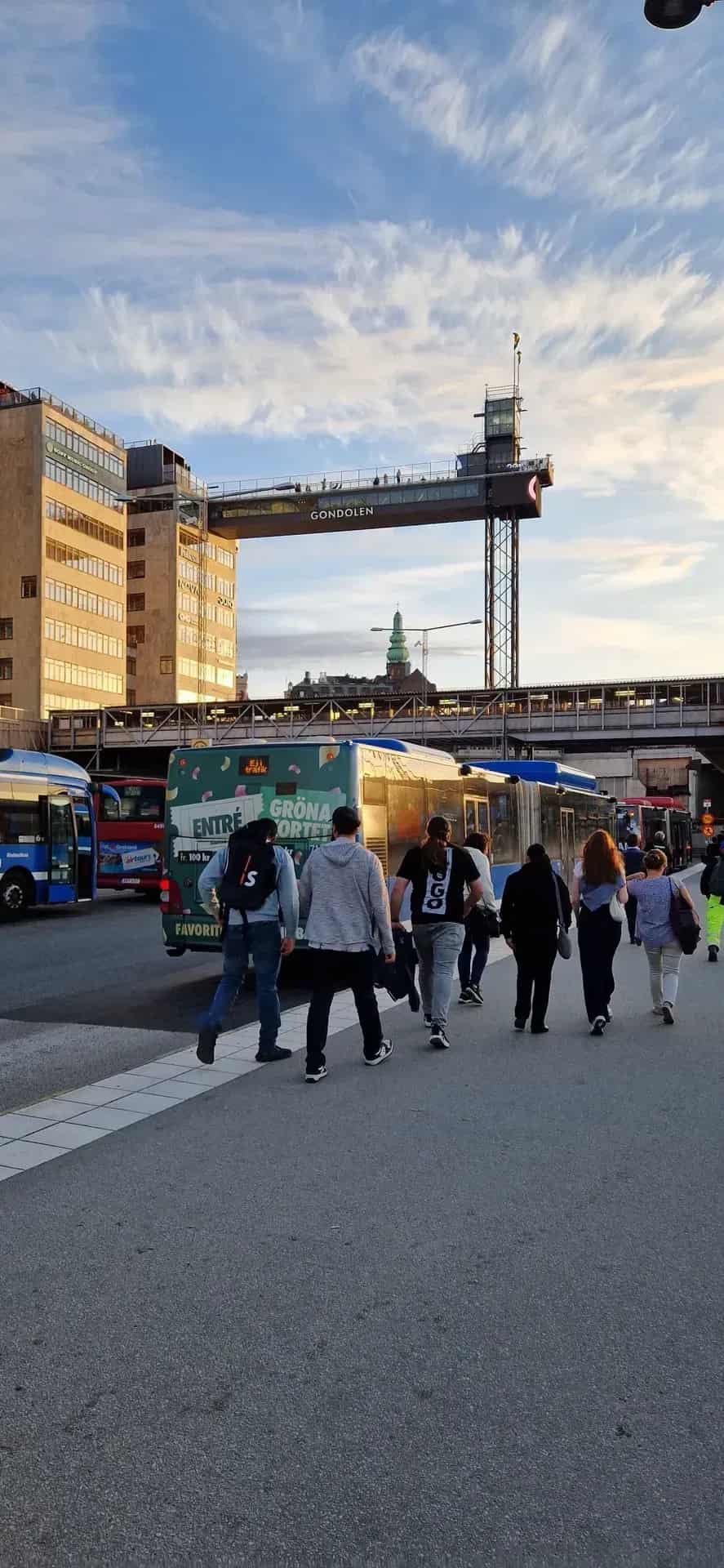 Gående passerar bussar vid byggnad med skylten Gondolen
