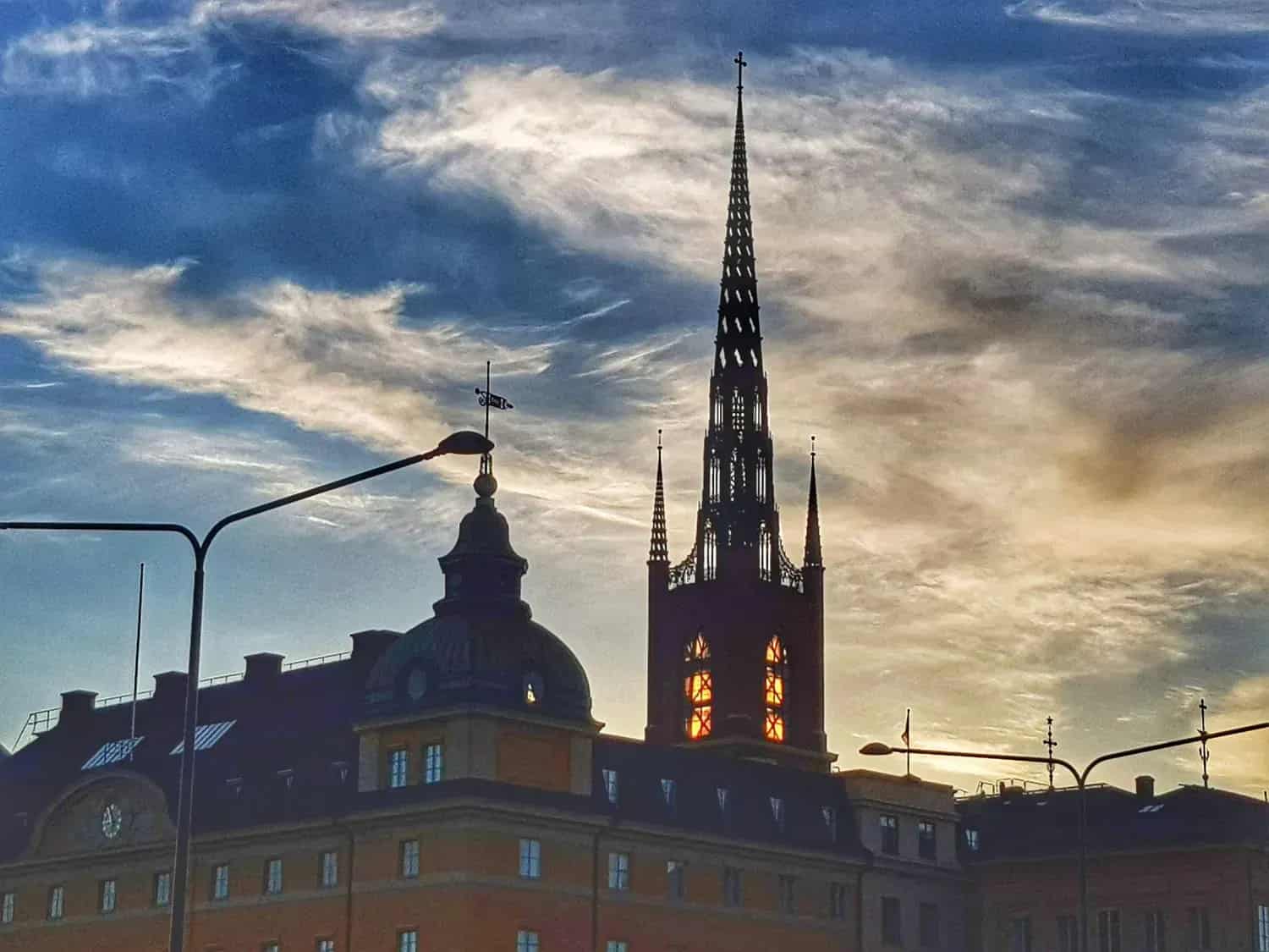 Siluett av byggnader, kyrktorn och himmel med moln